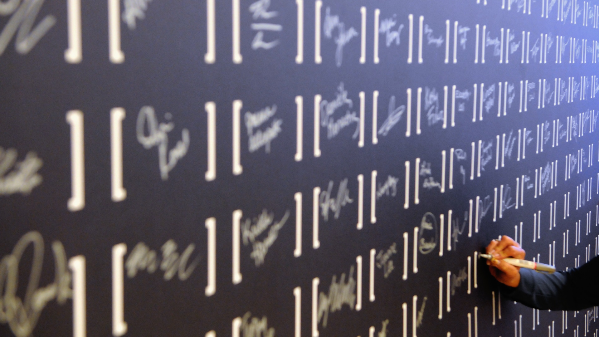 An employee writing his name on a wall at the brand launch event.