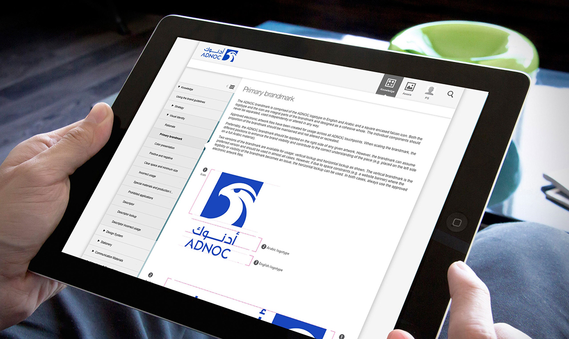 A man with a tablet in his hands with the brand management system designed and developed for ADNOC with BrandOS