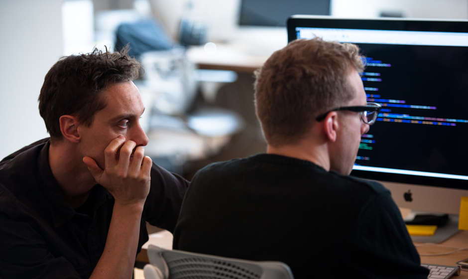 Two men integrating technology while sitting in front of a computer screen.