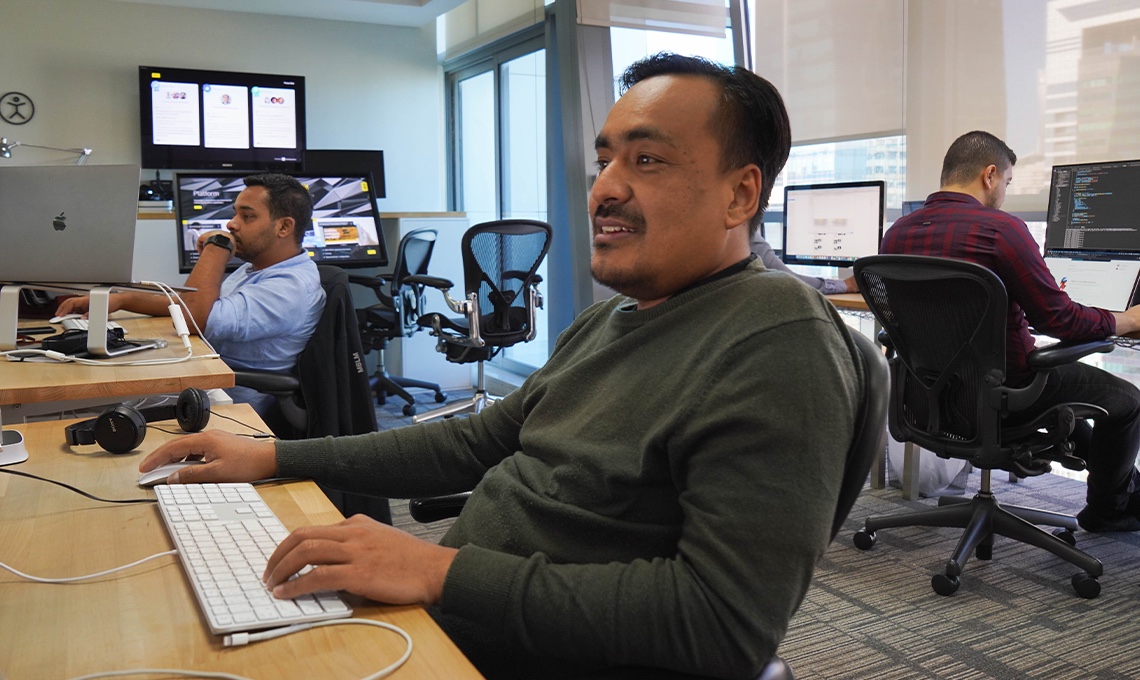 A man sits at a desk in front of several computers.