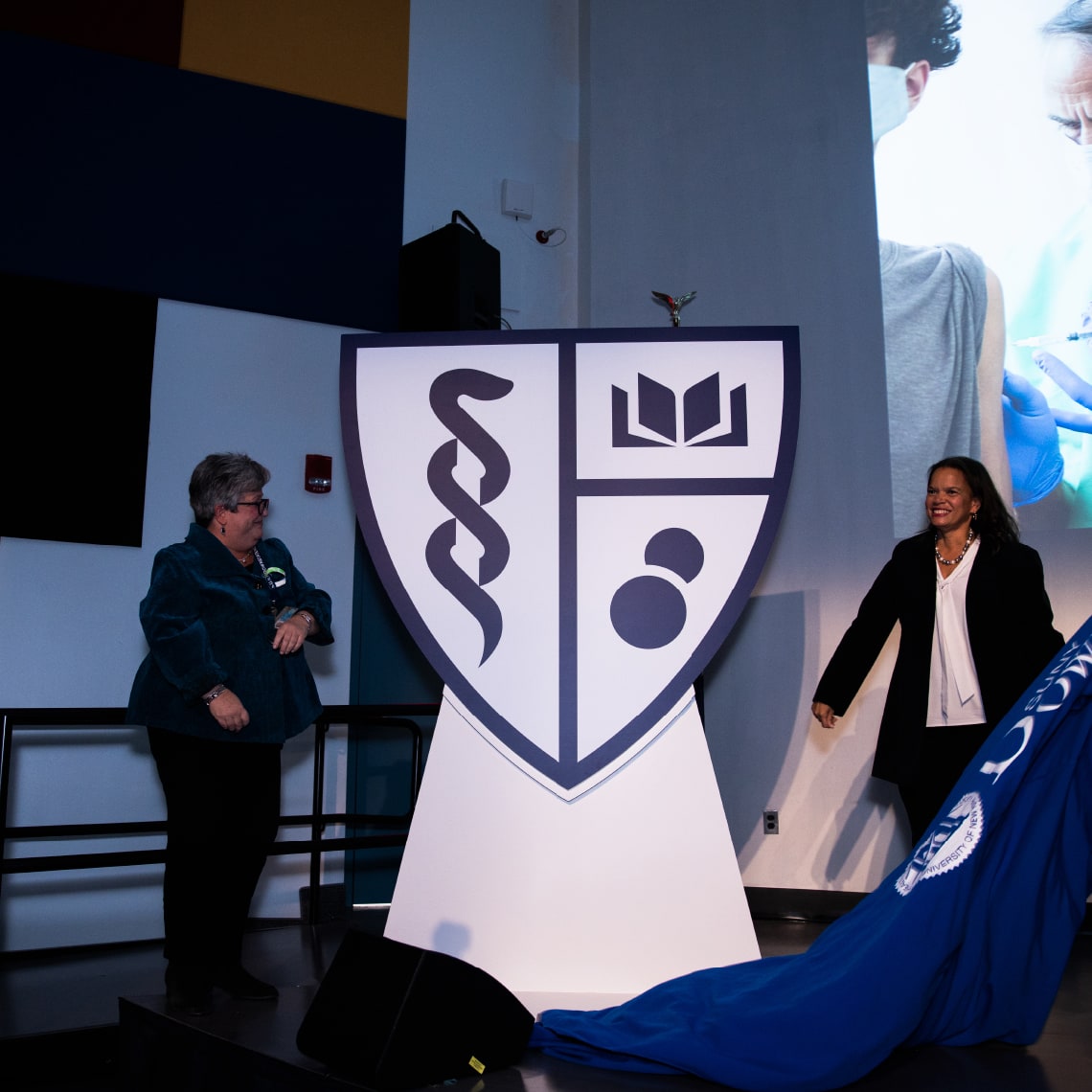 wo cheerful women unveiling the new logo designed for SUNY