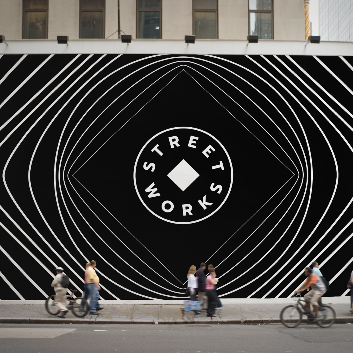 a group of people riding bicycles along a street in front of a black wall with the design system designed for Street Works applied in white
