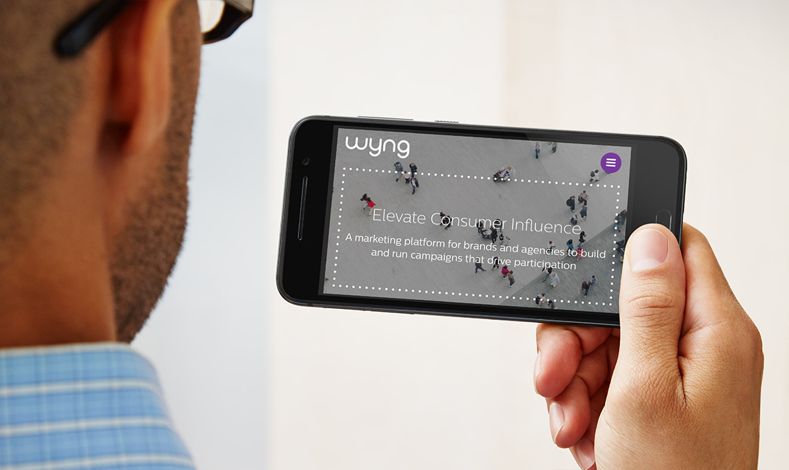 A man holding up a cell phone with a screen showing a group of people.