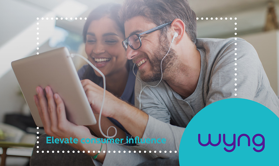 A man and woman are looking at a tablet while listening to music.