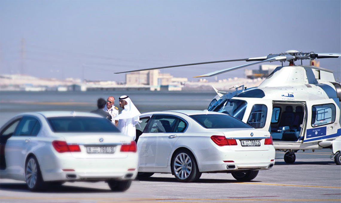 A helicopter is parked next to a white car.