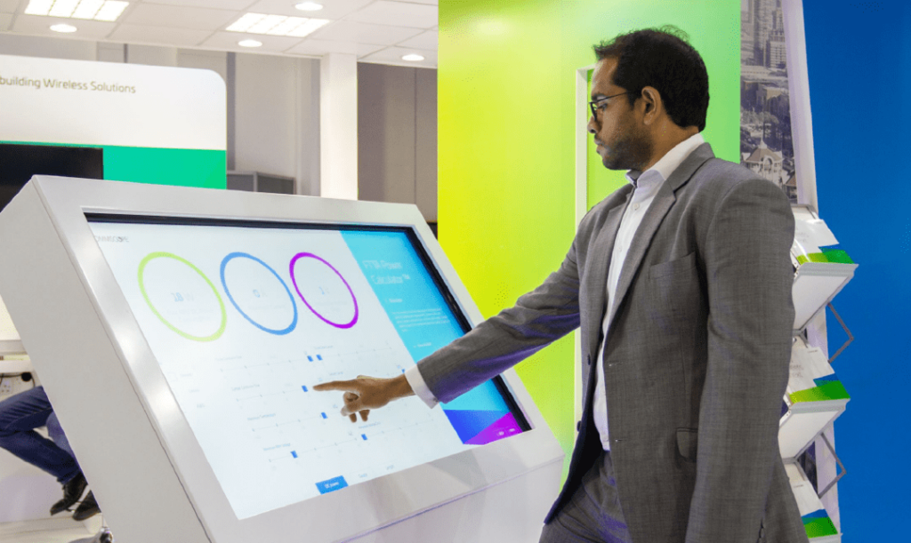 A man wearing a grey suit presenting in a conference.