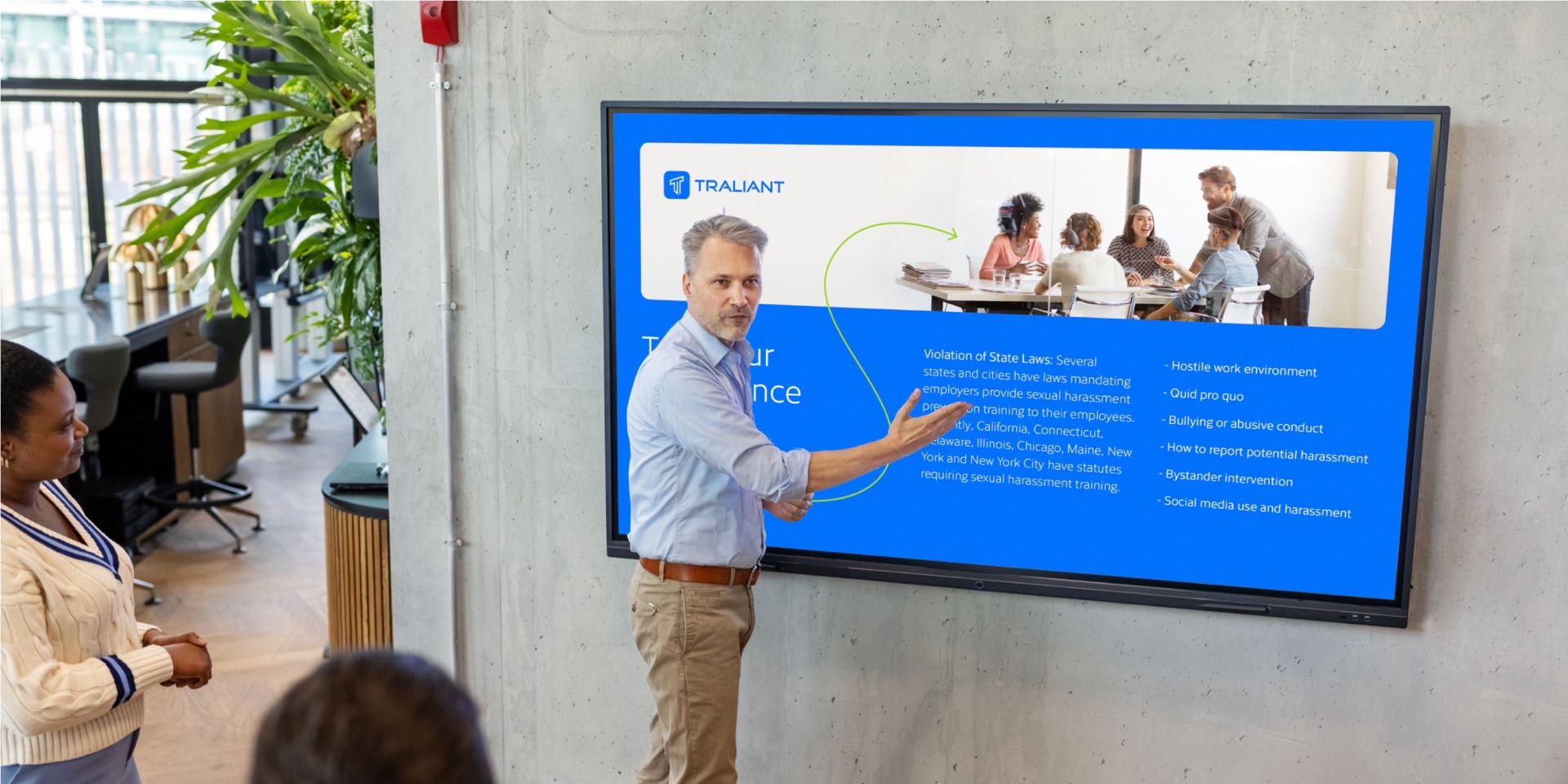 A person points to a screen displaying the presentation developed for Traliant