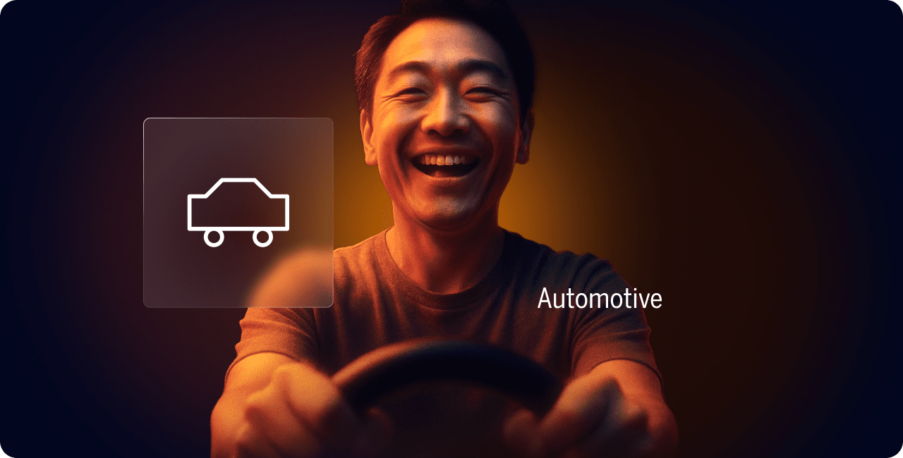 A smiling person holds a steering wheel, with a car icon and the word "Automotive" displayed beside them against a dark background.